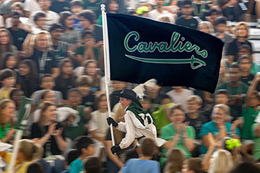 A student runs with the team flag, making the crowd cheer. Links to Gifts of Real Estate
