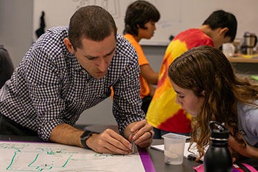 A man helping his student with a project. Links to Ages 45–65 A man helping his student with a project. Links to Ages 45–65
